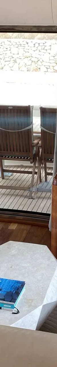 Een interieur van een boot met twee lichte banken, een salontafel, een tv en een open deur naar een buitendek. — Aicon 64