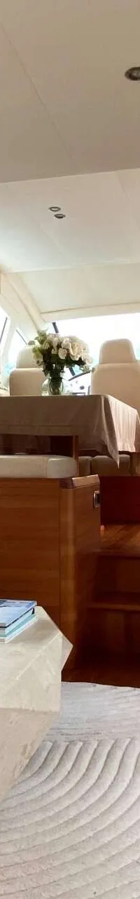 De foto toont het interieur van een boot met een zithoek, een salontafel, een eethoek en een stuurstand. — Aicon 64