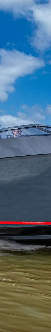 Een donkergrijze motorboot met de tekst "SALUT 38" en een rode streep op de zijkant vaart over water. — Salut 38