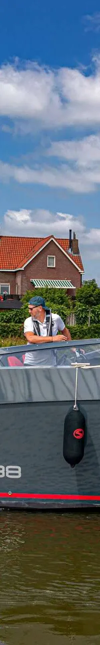 Een grijze motorboot met rode strepen en de tekst "SALUT 38" ligt aangemeerd, met twee mannen aan boord. — Salut 38