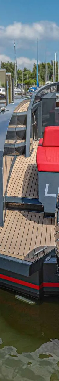 Twee boten liggen aangemeerd in een haven, met een witte boot aan de linkerkant en een grijze boot aan de rechterkant.