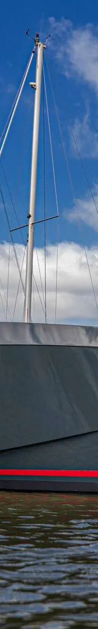 Een donkergrijze boot met een rode streep en de tekst "SALUT 38" ligt in het water, met een persoon aan boord. — Salut 38