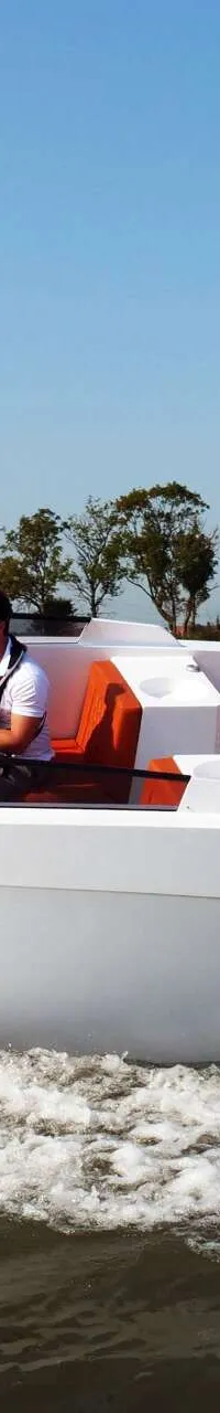Een witte boot met oranje kussens en de tekst "SALUT 29 DEMO" vaart over water met een man aan het stuur. — Salut 29