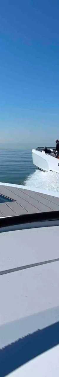 Vanaf een boot met grijze dekbekleding en een hand op de gashendel wordt een andere witte boot met buitenboordmotor gevolgd.