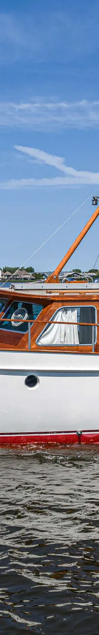 Een witte motorboot met houten opbouw en rode waterlijn vaart op een meer onder een blauwe lucht. — Kok Spitsgatkotter 16.50