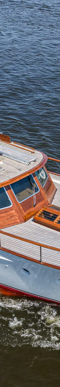 Een witte motorboot met houten opbouw en dek vaart op donkerblauw water. — Kok Spitsgatkotter 16.50