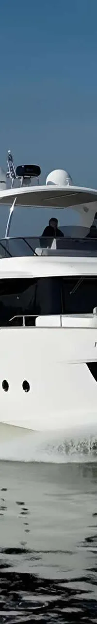 Een witte motorjacht met de naam "AMAN DEEP" vaart over rustig water, met een windmolenpark op de achtergrond.