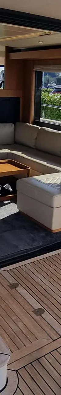 Een trap met houten treden en een metalen leuning leidt naar een salon met een bank en een tafel.