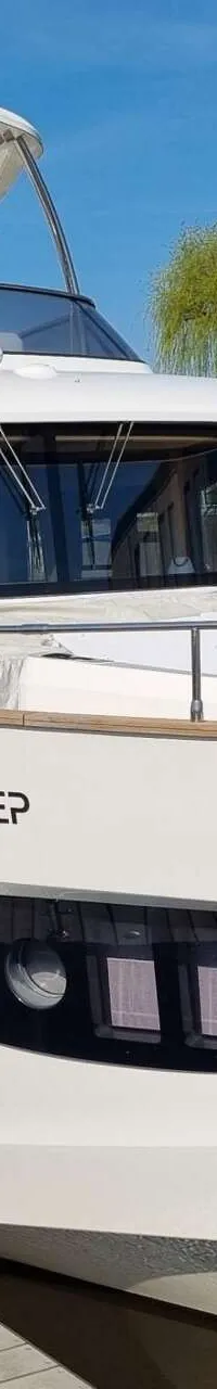 Een witte motorboot met de naam "AMAN DEEP" ligt afgemeerd aan een houten steiger. — Absolute Navetta 58 Trawler