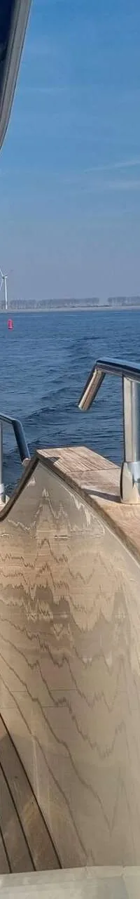 Een zijaanzicht van een boot met een houten dek en een metalen reling, varend op open water. — Absolute Navetta 58 Trawler