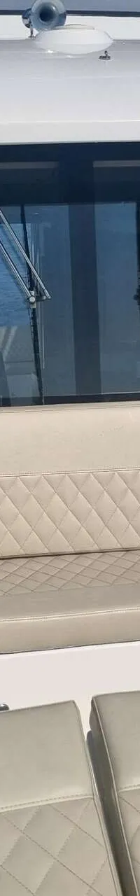 Een boot met beige, gestikte kussens op de banken en een groot raam met uitzicht op water. — Absolute Navetta 58 Trawler