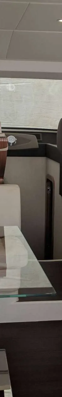 De foto toont het interieur van een boot met een zithoek, een glazen tafel en een stuurstand. — Ferretti 510