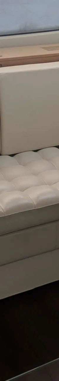 Een crèmekleurige bank met twee kussens staat in een kajuit met houten wanden en een raam. — Ferretti 510