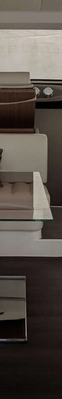 De foto toont het interieur van een boot met witte banken, een glazen tafel en een donkere vloer. — Ferretti 510