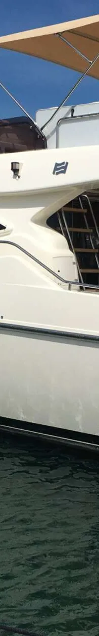 Een witte motorjacht met de naam "LADY MARIT" ligt aangemeerd in een haven, met een beige zonnescherm en zwarte stootwillen.