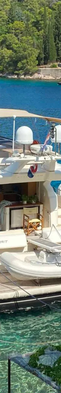 Een witte motorjacht met de naam "LADY MARIT" ligt aangemeerd in een baai met helderblauw water.