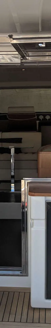 Een bootinterieur met een trap, schuifdeur, zitbanken, een tafel en een koelkast.