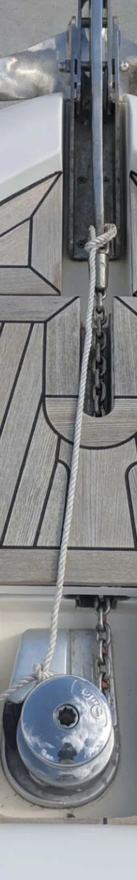 De foto toont de boeg van een boot met een teakhouten dek, ankerlier, anker en bolders. — Ferretti 510