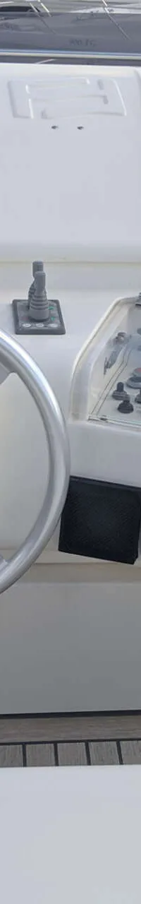 Een witte stuurstand met een zilverkleurig stuurwiel, een gashendel en diverse instrumenten.