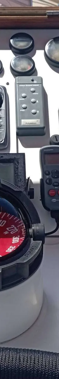 Een stuurstand met diverse navigatie-instrumenten, waaronder een kompas, twee marifoons en een motorbediening.