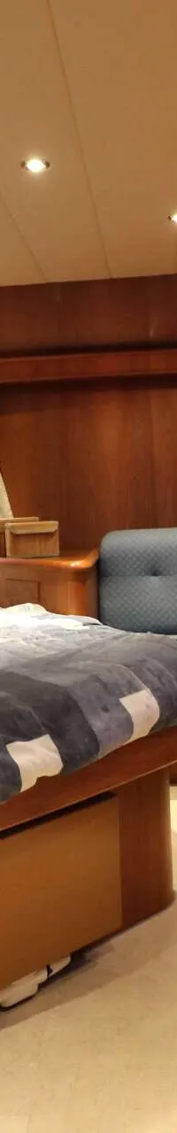 Een slaapkamer met een tweepersoonsbed, houten wanden en kasten, en een raam met gordijnen.