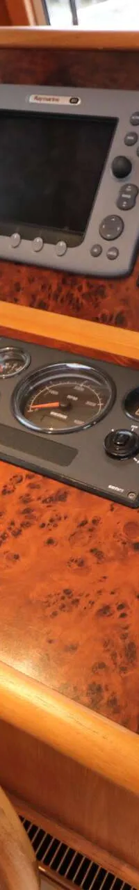 Een houten stuurwiel en een dashboard met diverse meters, schermen en bedieningselementen zijn zichtbaar.