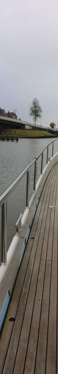 Een boot met een houten dek en een reling vaart langs een brug over een waterweg. — Boarncruiser 50 Classic Line