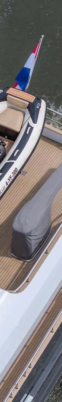 Een bovenaanzicht van de achterkant van een boot met een bijboot, een Nederlandse vlag en een Simrad radar.