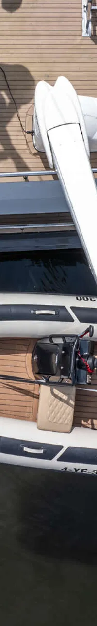 Een opblaasbare bijboot met buitenboordmotor ligt naast een groter jacht, gezien van bovenaf. — Bloemsma Trawler 70