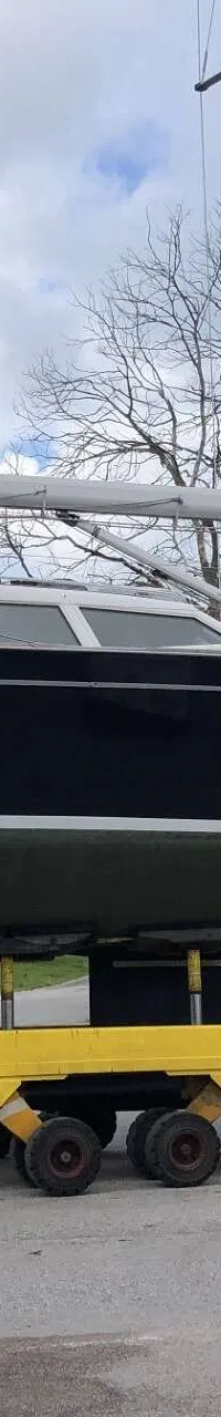 Een donkerblauwe zeilboot met de naam "nordbaelt 50" staat op een gele trailer op een weg. — Nordbaelt 50
