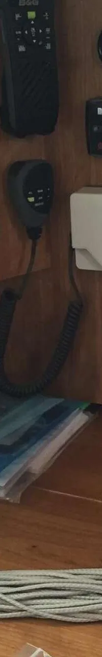 Een houten paneel met diverse navigatie-instrumenten, schakelaars, stopcontacten en een opgerolde kabel.