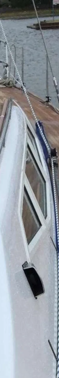 Een roestvrijstalen fornuis met oven en vier gaspitten is ingebouwd in een houten keukenblok met grijs aanrechtblad.
