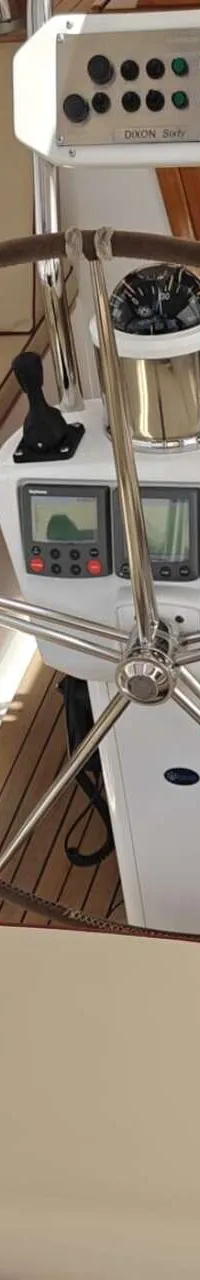 Een stuurstand met een groot stuurwiel, kompas en navigatie-instrumenten, omringd door beige zitkussens met rode biezen.