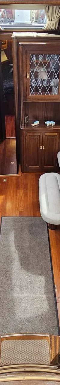 De foto toont het interieur van een boot met houten wanden en vloer, zitbanken met kussens en een tafel. — Premier Dixon  62