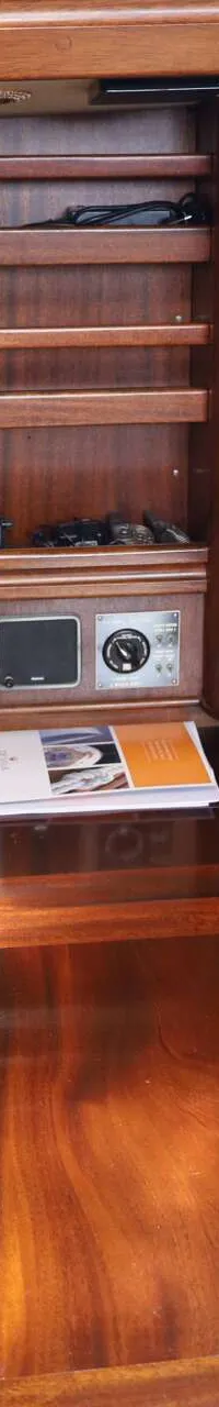 De foto toont een houten interieur met een bed, een bureau, een paneel met schakelaars en meters, en diverse elektronische…