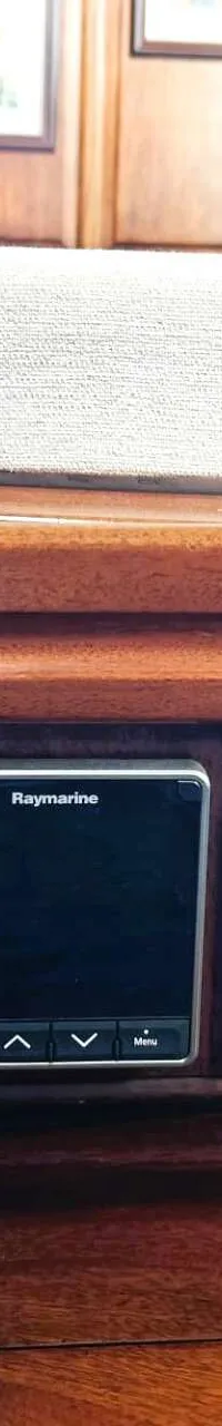 Een houten dashboard met vier Raymarine-schermen en een Navtex Plus-apparaat.