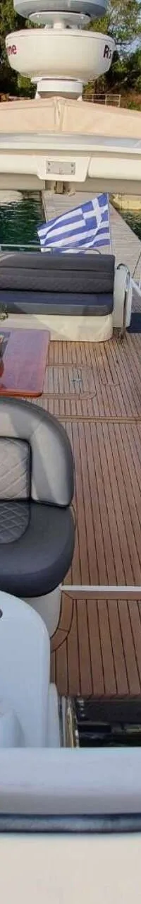 Een bovenaanzicht van een boot met een stuurstand, zitplaatsen, een tafel en een Griekse vlag aan de achtersteven.
