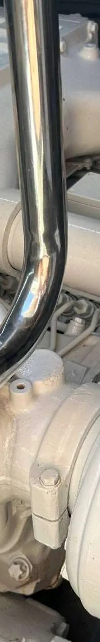 Een close-up van een scheepsmotor met veel witte en zilverkleurige onderdelen, leidingen en filters.