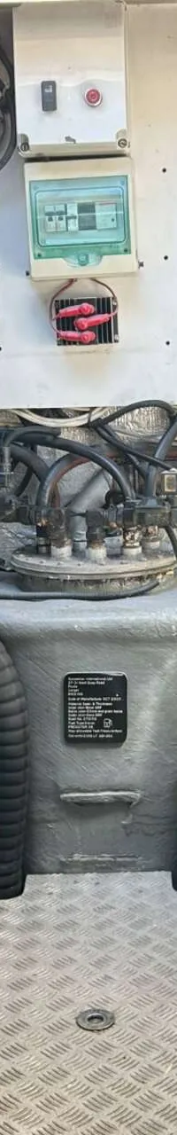 De foto toont een machinekamer met twee grote, witte motoren aan weerszijden van een gangpad met een geribbeld metalen vloer.