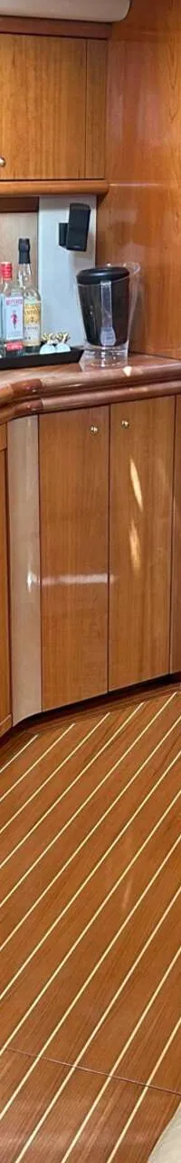 Een interieur van een boot met een houten keukenblok, een tafel en een doorgang naar een slaapruimte. — Sunseeker Predator 56