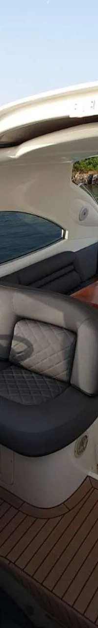Een jacht met een stuurstand, zitplaatsen, een tafel en een Griekse vlag, liggend aan een steiger. — Sunseeker Predator 56