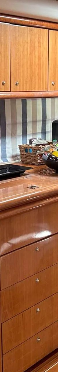Een houten kombuis met aanrecht, kasten, laden, een gootsteen, een kookplaat, een magnetron en een koelkast.