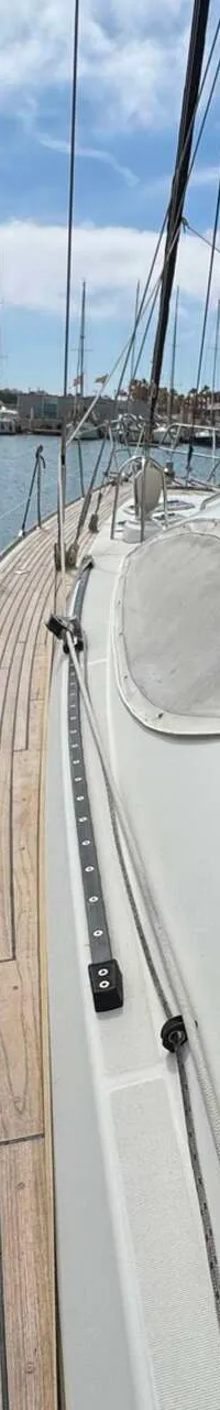 Een zeilboot ligt aangemeerd in een haven, met een teakdek en een blauwe buiskap. — Jeanneau Sun Odyssey 54 DS