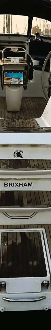 De achterkant van een witte zeilboot met de naam "SPARTA" en "BRIXHAM" is zichtbaar, inclusief een Yamaha buitenboordmotor…