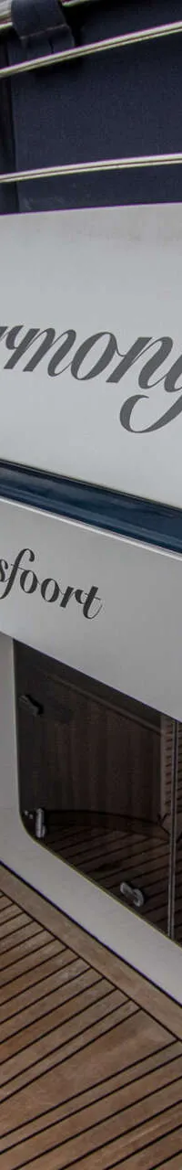 De spiegel van een boot met de namen "Harmony" en "Amersfoort" is zichtbaar, met een teakdek en een donkere waterpartij.