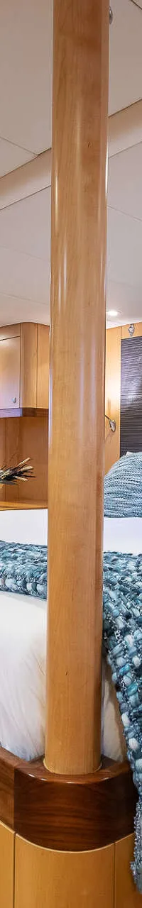 Een ruime kajuit met een tweepersoonsbed, een bank, een bureau en houten wanden en kasten. — Nordia 70 Performance Cruiser
