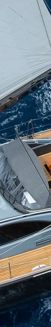 Een zeilboot met een houten dek en zeilen is te zien vanuit de lucht, met mensen aan boord. — Nordia 70 Performance Cruiser