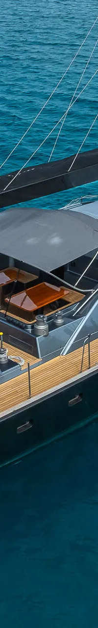 Een zeiljacht met de naam "KIGAI" en een Britse vlag aan de achtersteven, ligt in helderblauw water.