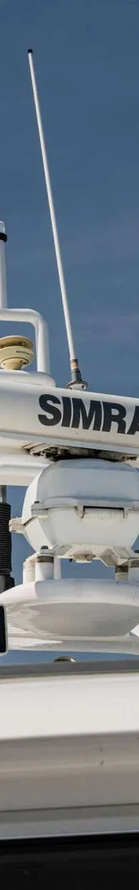 Een witte radar van het merk Simrad, twee witte antennes en twee witte koepels zijn zichtbaar op het dak van een boot.