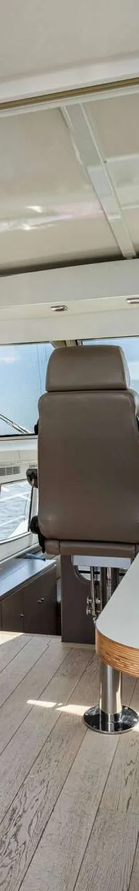 Een interieur van een boot met een stuurstand, een tafel met bank en kasten, en grote ramen rondom. — Vripack 63 Custom M/Y